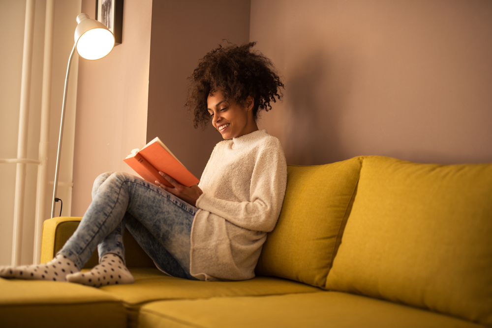 Young african american woman reading a book at home.