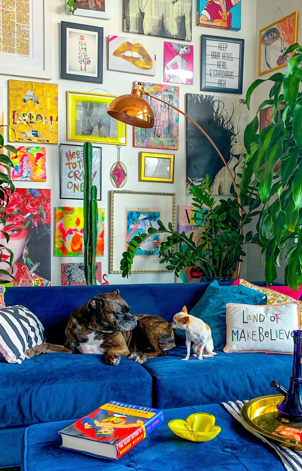 sala com sofá azul e parede de quadros coloridos
