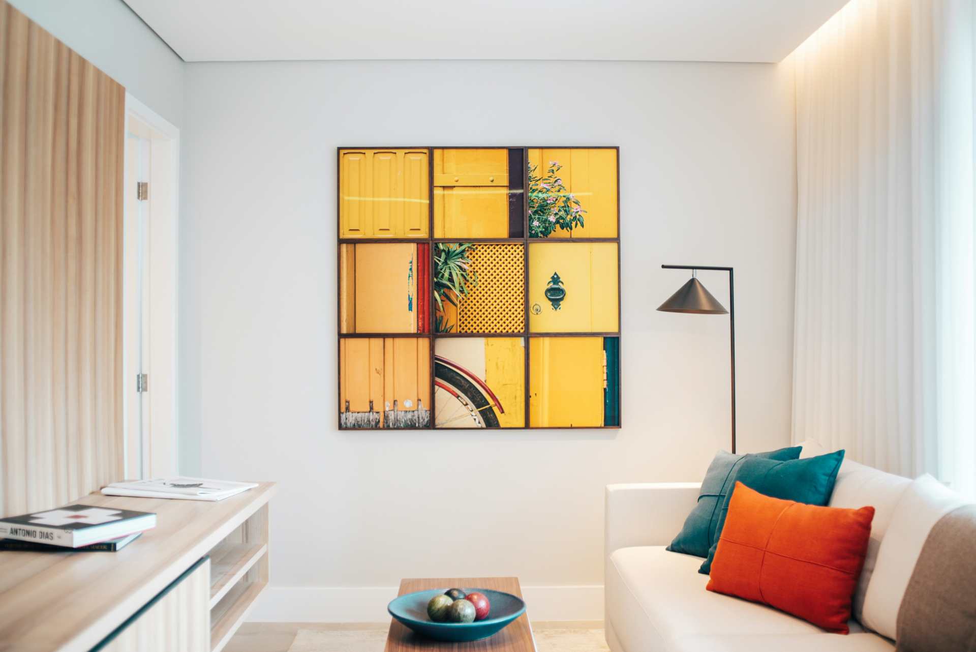 sala com parede e sofá neutros contrastando com almofadas e quadro coloridos