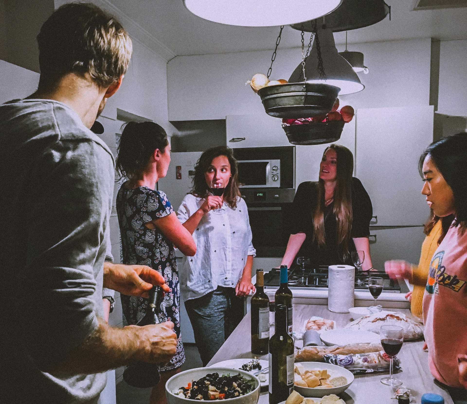 amigos conversando na cozinha ao lado de bancada com petiscos e bebidas