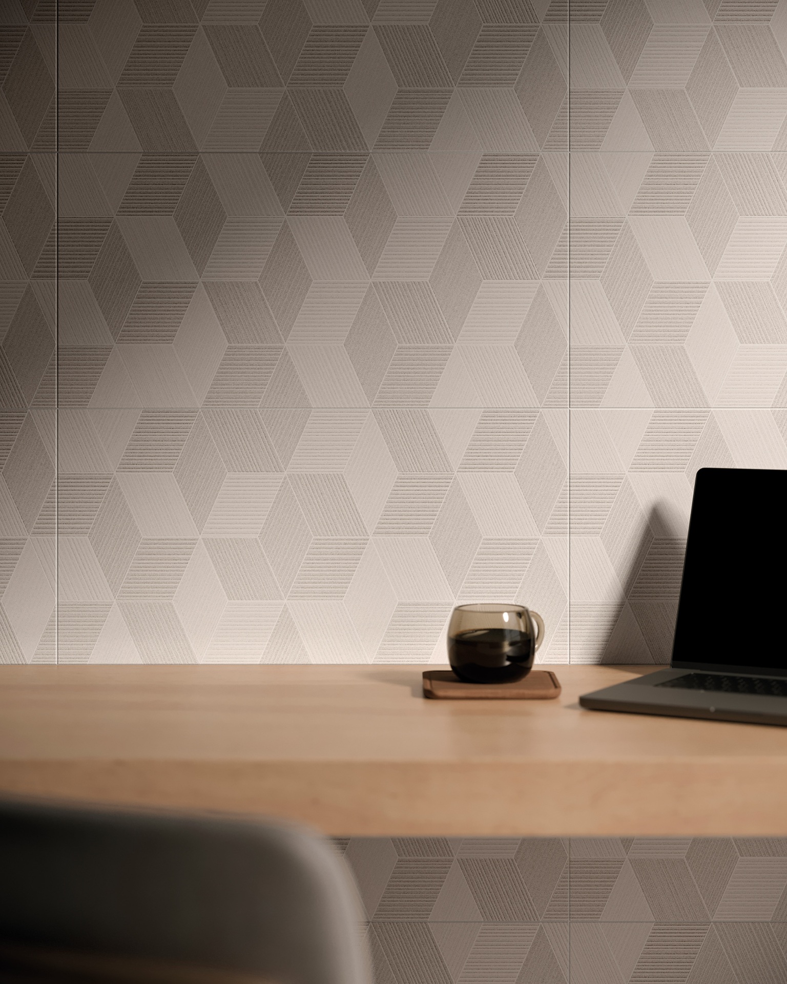 mesa de madeira com xícara de café e computador e parede revestida com cerâmica geométrica ao fundo