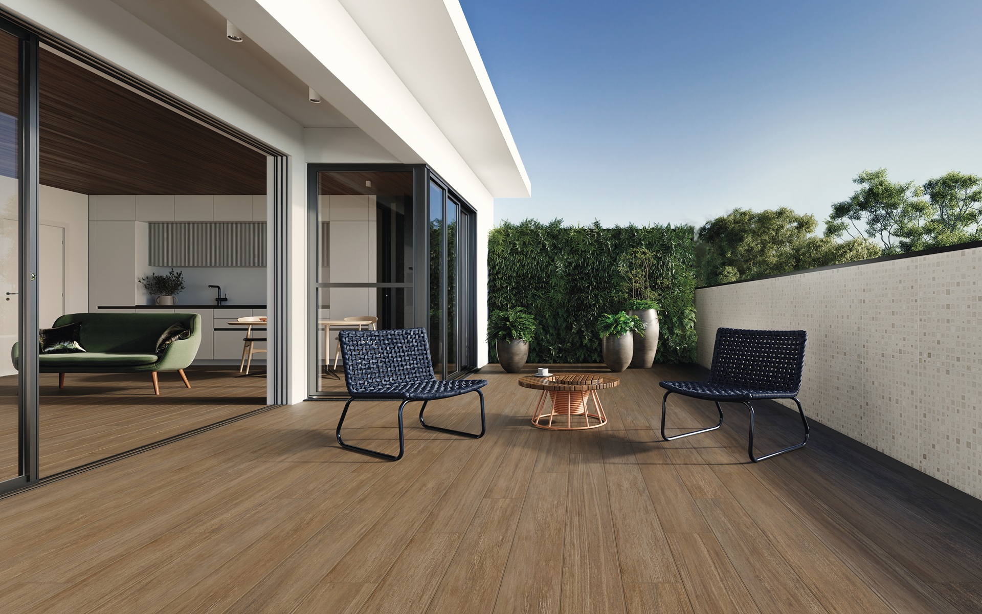 Varanda integrada com piso cerâmico amadeirado Pointer e poltronas de fibra natural escura ao redor de uma mesa de centro de madeira.