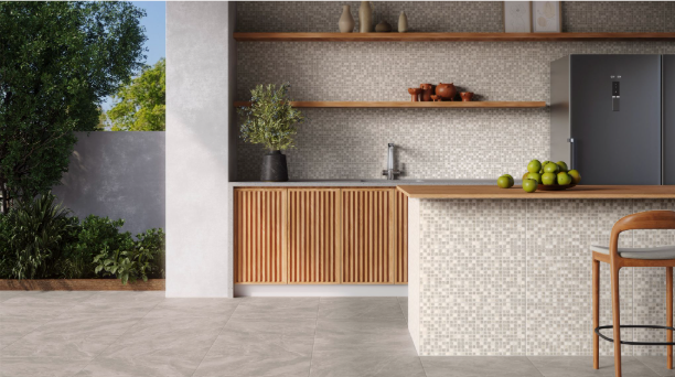 Cozinha gourmet integrada com área externa mostrando continuidade visual do piso cinza em tom cimento, bancada com revestimento quadriculado e marcenaria em madeira.