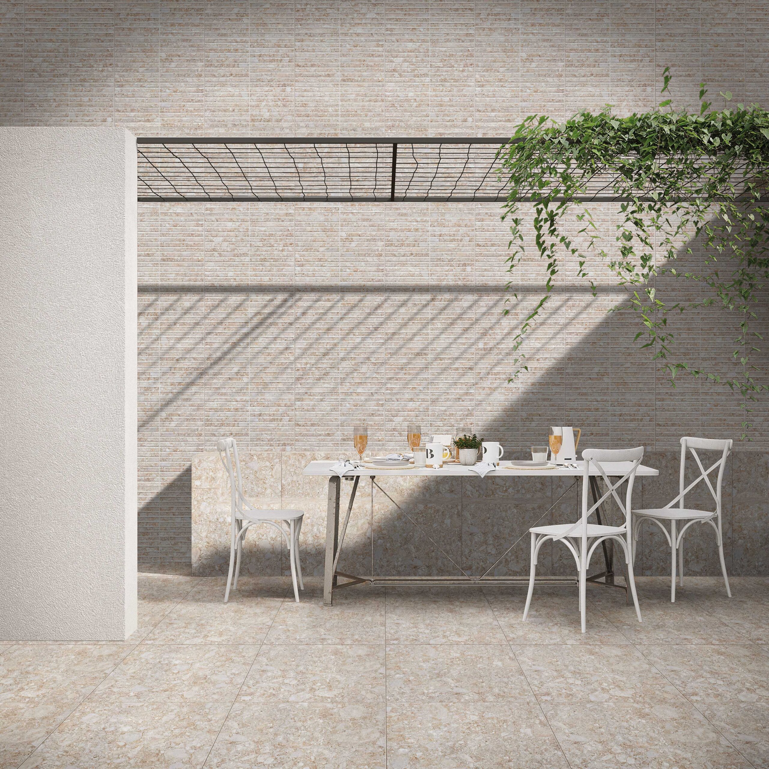 Terraço moderno com piso cerâmico que imita pedra, parede revestida em cerâmica texturizada, mesa de jantar de madeira e ferro, cadeiras brancas estilo bistrô e pérgola com planta trepadeira.
