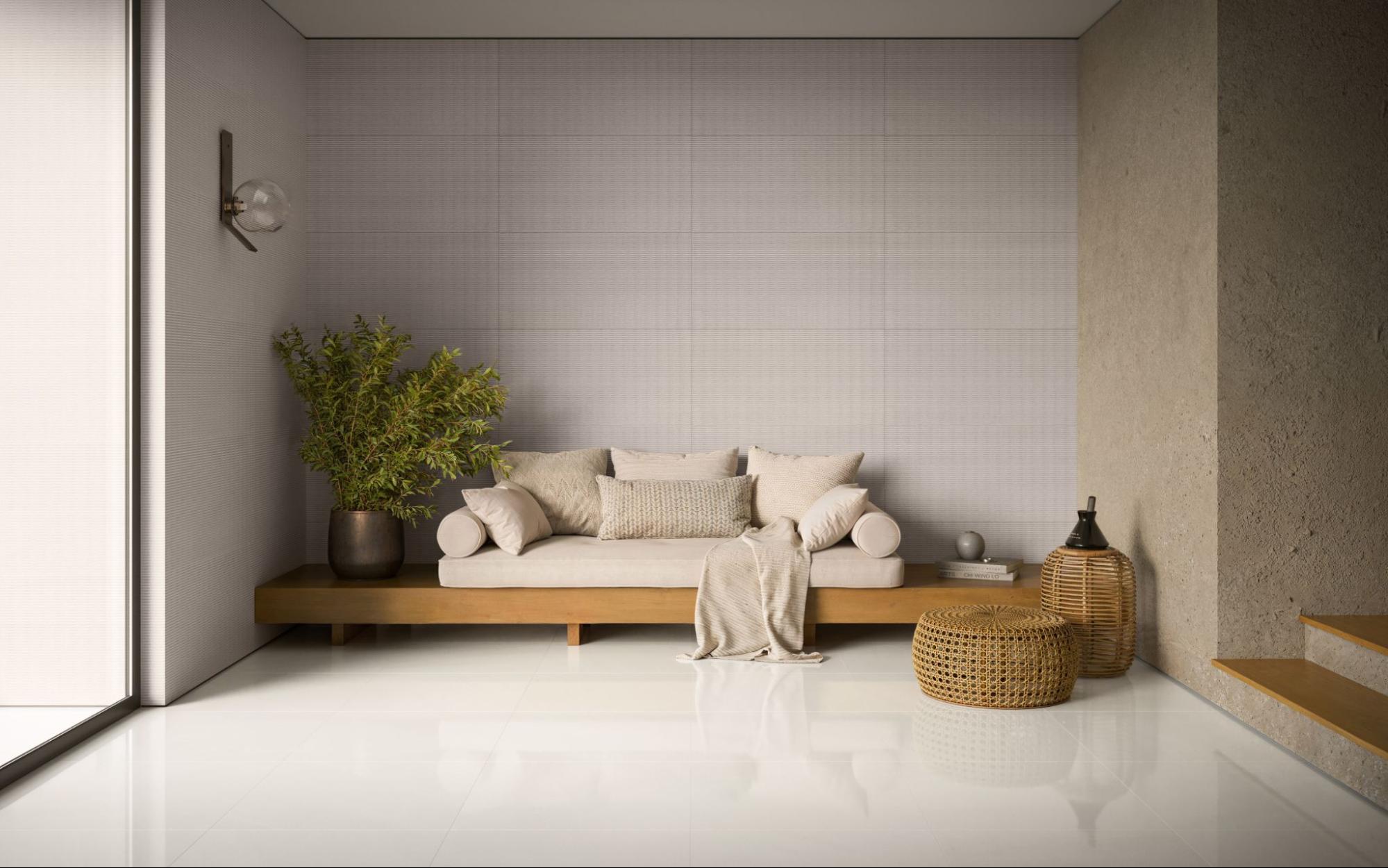 Sala de estar minimalista com piso de cerâmica branca brilhante, divã de madeira com almofadas de linho e móveis de fibra natural trançada (pufes). Parede com textura sutil e planta grande em vaso de metal.
