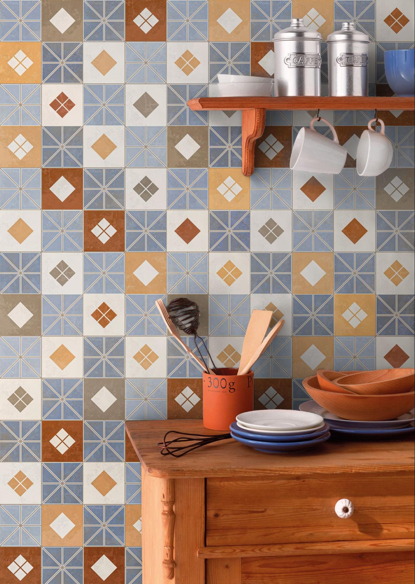 Piso e parede de cozinha decorada com revestimento Onix Pieces da Pointer, apresentando padrão geométrico em tons de azul, terracota, mostarda e cinza. Em primeiro plano, uma bancada de madeira rústica com utensílios e pratos.